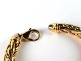 a close up of a gold bracelet on a white surface