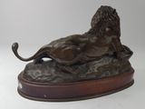 statue of a lion resting on a rock on a white background