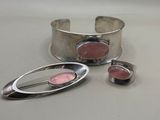 two silver cuff bracelets with pink stones on a white surface