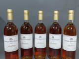 six bouteilles de vin sont alignées sur une surface grise