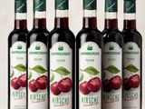 quatre bouteilles de vin rouge accompagnées de cerises sur une table