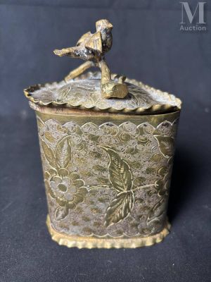 une boîte ancienne en laiton sur laquelle est perché un oiseau