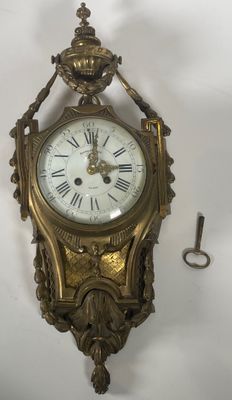 une horloge accrochée au mur, devant laquelle se trouve une clé