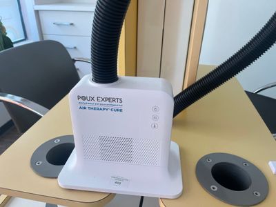 un purificateur d'air blanc posé sur une table, muni d'un tuyau noir