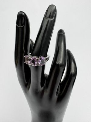 une main sur laquelle est passée une bague sertie d'une pierre violette