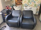 two black chairs in a room with a sink and a mirror