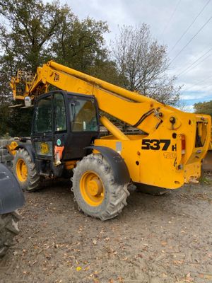 the back end of a yellow construction vehicle parked in a dirt lot