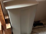 a white trash can sitting on the floor next to a stair