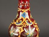 un vase rouge orné de motifs dorés et bleus