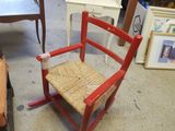 a red rocking chair with a wicker seat in a room