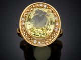 a close up of a yellow sapphire and diamond ring on a black surface