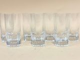 quatre verres transparents sont alignés sur une surface blanche
