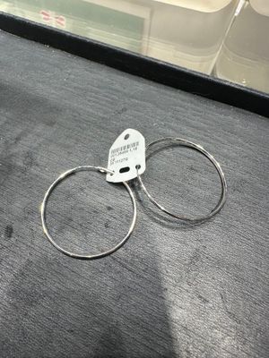 une paire de boucles d'oreilles créoles en argent ornées d'une étiquette