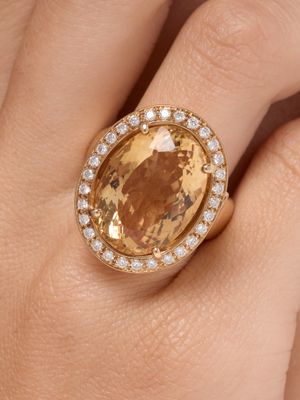 an image of a woman ' s hand holding a ring with a large yellow stone