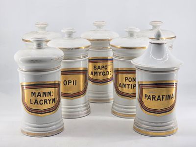 six white and gold canisters with labels on them on a white surface