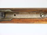 a close up of a rifle with a wooden handle on a white surface