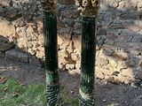 deux socles verts et dorés devant un mur de pierre