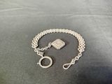 a close up of a silver chain bracelet with a square stone on it