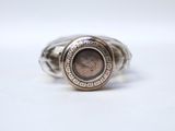 a close up of a silver ring with a coin on it