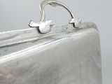 a silver metal bag with a handle on it