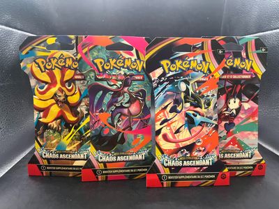 trois paquets de cartes Pokémon posés sur un canapé