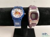 two wrist watches on display on a black stand