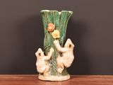 un vase en céramique orné de deux ours et contenant une fleur