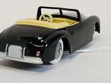 a black toy car with a yellow top on a white surface