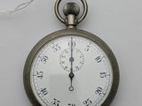 une montre de poche en argent accrochée à un mur blanc