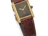a close up of a watch on a white surface with a brown strap
