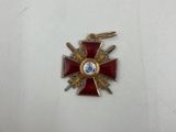 une croix rouge et dorée ornée d'un diamant