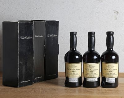 trois bouteilles de vin posées à côté d'une boîte noire sur une table en bois