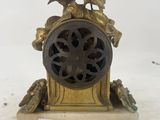 two birds sitting on top of a clock on a table