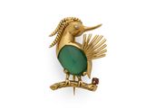 une image représentant une broche en forme d'oiseau doré et vert posée sur une branche