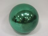 une boule de verre verte brillante posée sur une surface blanche