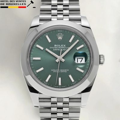a close up of a watch with a green dial on a bracelet