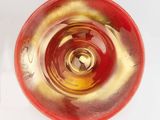 underside view of a red and gold glass bowl on a white surface