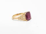 a close up of a gold ring with a ruby stone and diamonds