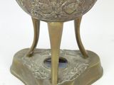 a silver vase with a bird on it on a stand