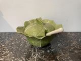 a green cabbage bowl with a wooden spoon in it