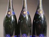 trois bouteilles de champagne sont alignées sur une table