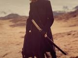 a woman in a black coat holding a baseball bat in a field
