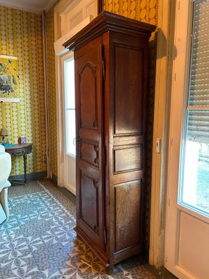 a tall wooden cabinet in the corner of a room