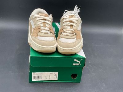 pair of puma sneakers in box on grey surface with green box