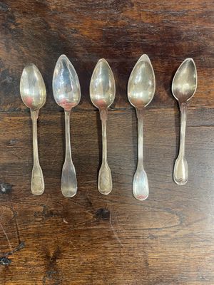 six silver spoons lined up in a row on a wooden table