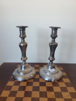 deux bougies argentées posées sur un échiquier posé sur la table
