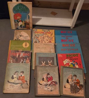 Plusieurs livres pour enfants sont alignés par terre, à côté d'une étagère