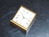a small clock sitting on a marble table top