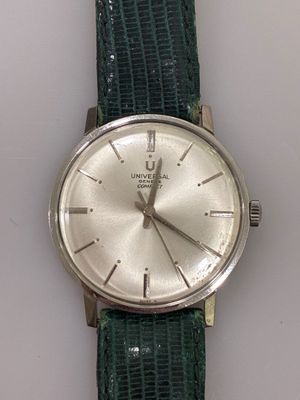 a silver watch on a green strap on a white surface