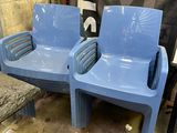 two blue plastic chairs sitting next to each other in a room